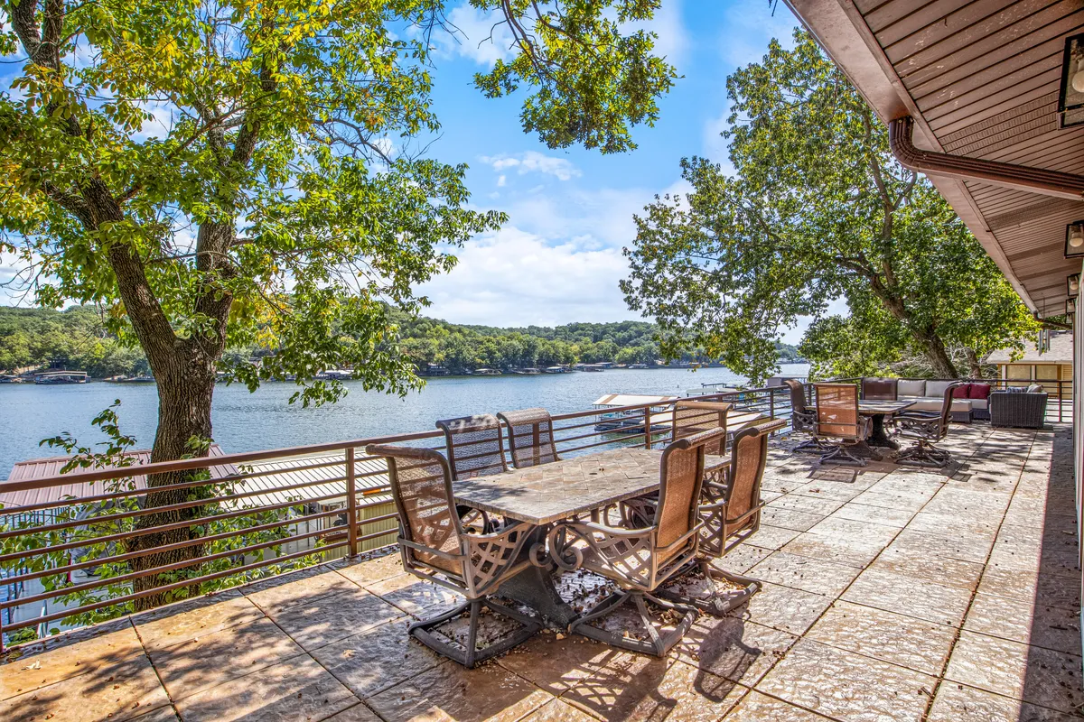An outdoor dining area with a table and seating set against a serene lake backdrop. Trees provide a natural frame, and the space is clearly designed for group meals, celebrations, or simply relaxing with a view.