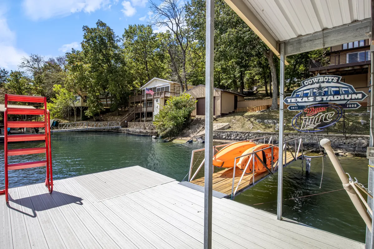 A cheerful lakeside scene featuring a red ladder, an orange kayak ready for adventure, clear water, and trees and houses in the background. The playful mood is evident, perfect for families and water sports enthusiasts.